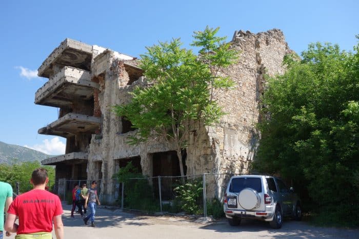 Mostar: Discovering the scars of the war that rocked Bosnia. The bombed out buildings that remain, Bosnia and Herzegovina, Bombed out buildings, sniper towner, exploring the sniper tower, how to get in, is it safe, mountains, cross, view from sniper tower, bullet holes, yugoslavia, balkan war, siege, fighting, croats, serbs, bosnians, muslims, front line, history