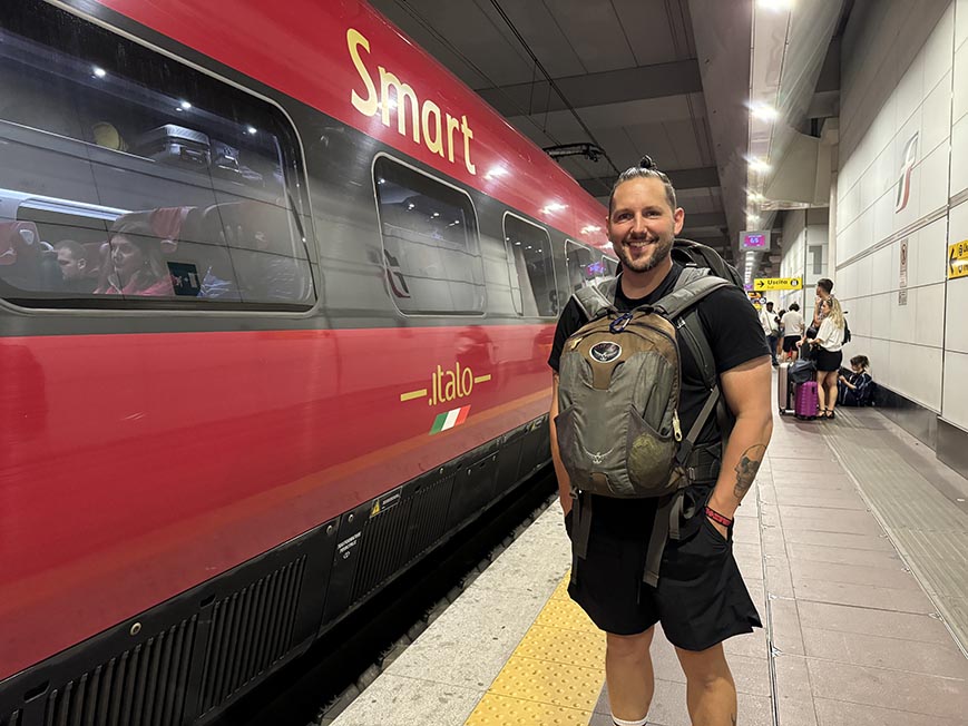 Shorty waiting for a train with his backpacks on in Italy.