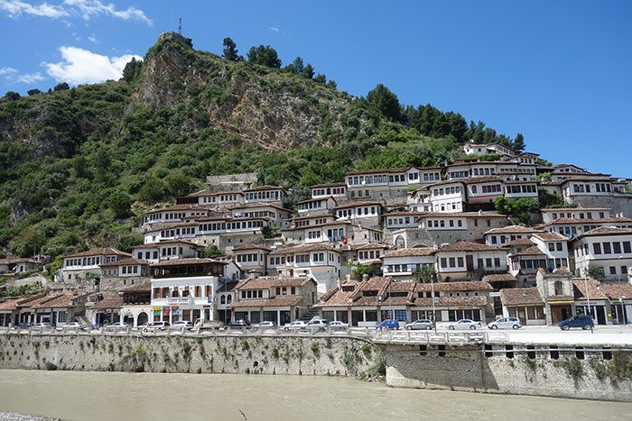 Looking across the river in Berat, Albania and the thousand windows of the old town and a small mountain/ hillside behind them.