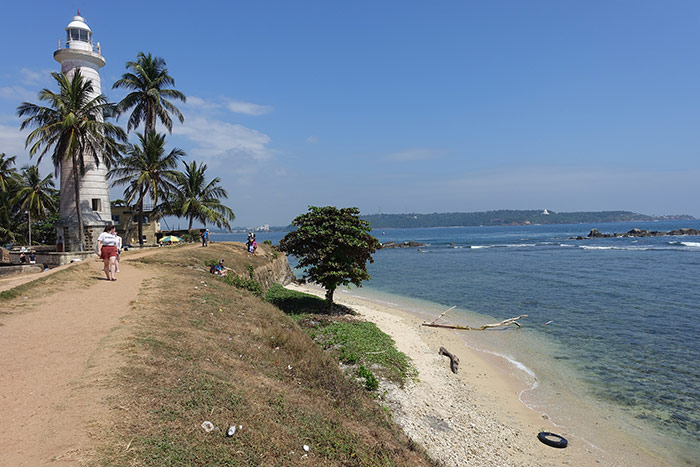 The path that goes towards the main light house along the coast in Galle, Sri Lanka with the clear blue sea water next to it.