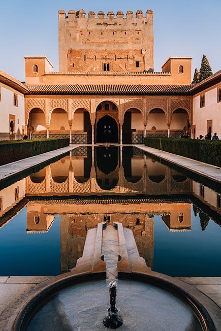 Looking out at the main pool of Alhambra with the large gateway reflecting perfectly in it on a clear sunny day
