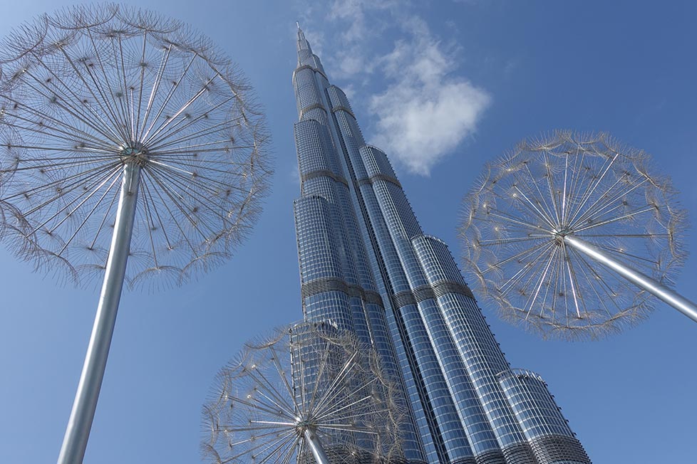 The Burj Khalifa on a clear blue day from below with metal dandelions around it
