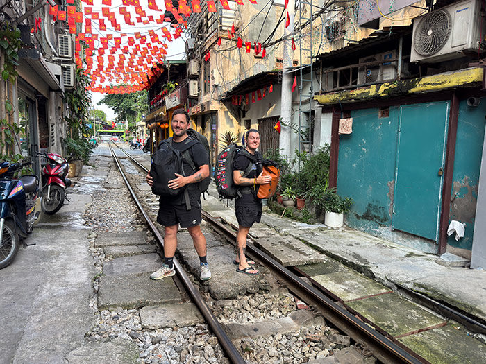 Nic and Shorty carrying their backpacks on train street in Hanoi. Packing list for Southeast Asia. 
