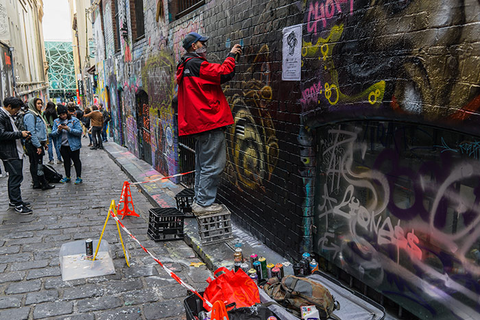 An artist at work doing some graffiti on one of Melbourne's best street art spots, otherwise known as graffiti lane Melbourne