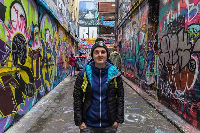 Nic standing on a laneway in Melbourne surrounded by graffiti and street art